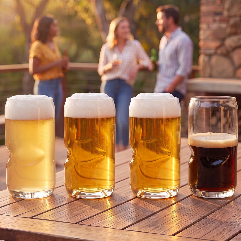 Four Govino shatterproof beer can glasses on a wooden deck table with friends braaiing behind