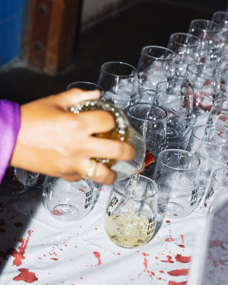 Wine being poured into rows of Govino stemless glasses at a large event
